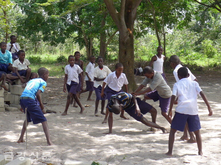 흙바닥에서 축구를 하고 있는 아이들.