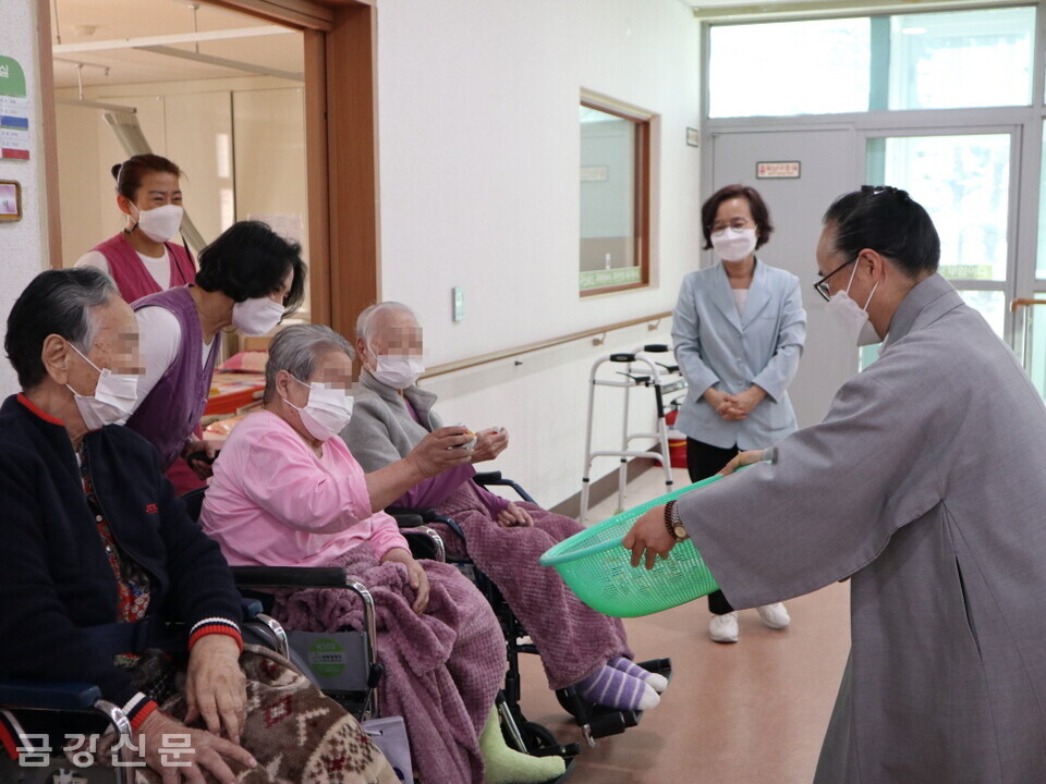 성문노인요양원장 일지 스님이 어르신들에게 부럼을 나눠주고 있다. 