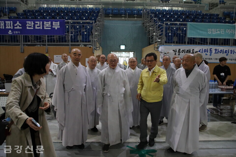김홍규 강릉시장의 안내를 받으며 이재민 임시대피소로 활용되고 있는 강릉 아이스아레나를 방문하고 있는 스님들.