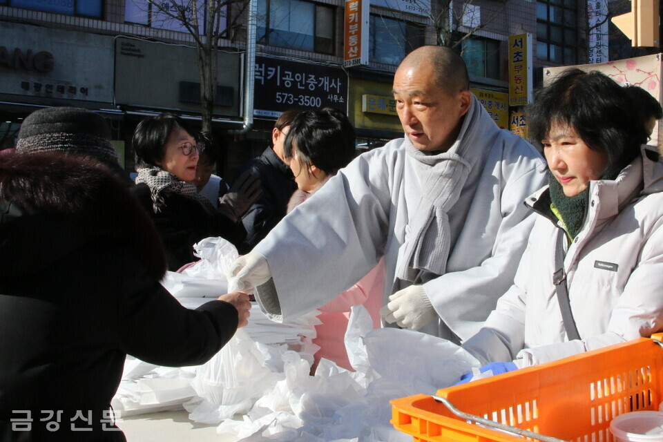 관문사 재무 도각 스님과 불자, 우면종합사회복지관 직원들이 주민들에게 팥죽을 나눠주고 있다.